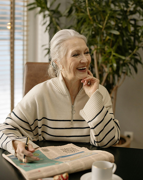 grey-haired woman reading newspaper